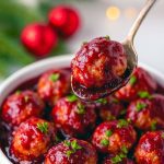 Glossy cranberry-glazed meatballs piled on a festive platter, garnished with chopped parsley and ready for serving.